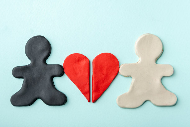 用黑白橡皮泥做成的小人手里拿着半瓣蓝色背景的红色橡皮泥心图片下载