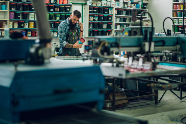男工人在车间里用智能手机为丝网印刷调色图片下载