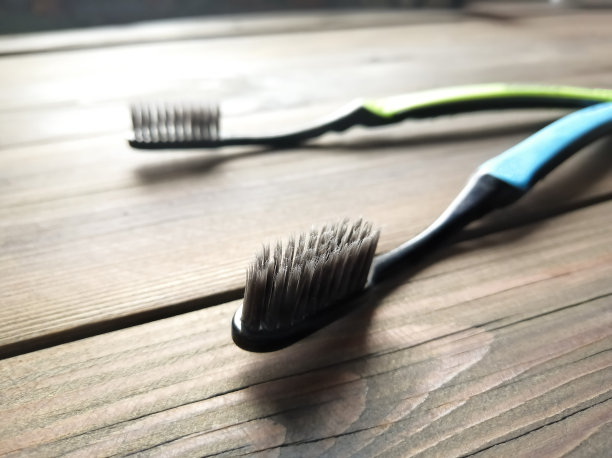 木桌上放着两把牙刷。光线从正面照射下来。活性炭牙刷。图片下载