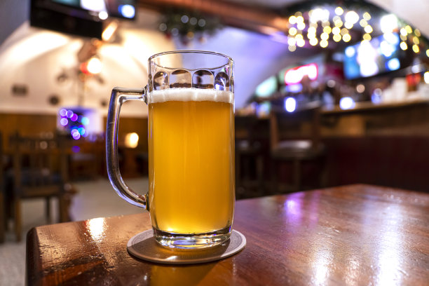 满杯的淡啤酒在温暖的灯光下木制的桌子。酒类、娱乐、传统饮品、啤酒节氛围概念。现代的酒吧。休息。图片下载