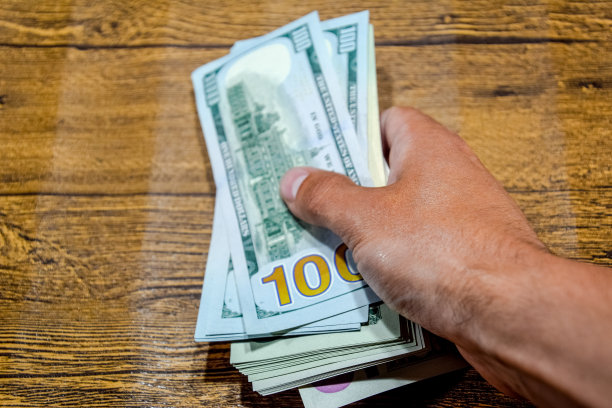 桌子边的男人拿着账单。美元的手。图片下载