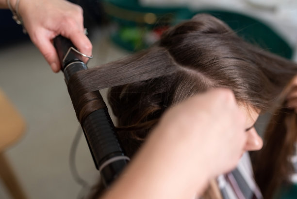 发型师用卷发器把女孩的头发卷起来图片下载