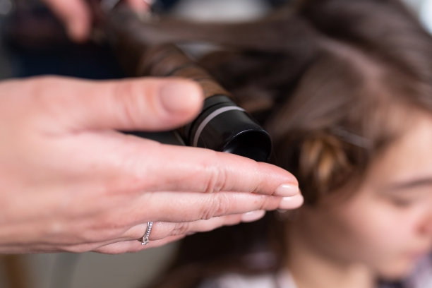 发型师用卷发器把女孩的头发卷起来图片下载