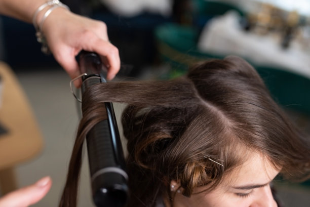 发型师用卷发器把女孩的头发卷起来图片下载