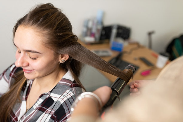 发型师用卷发器把女孩的头发卷起来图片下载