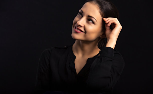 美丽自信快乐微笑的商业妇女与手近脸仰望黑色背景与空的拷贝空间。特写肖像图片下载