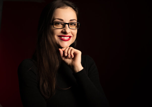 美丽的牙齿微笑着快乐的商业女人红色的口红看起来快乐在休闲黑色污染在暗红色的背景与空复印空间的眼镜。特写镜头图片下载