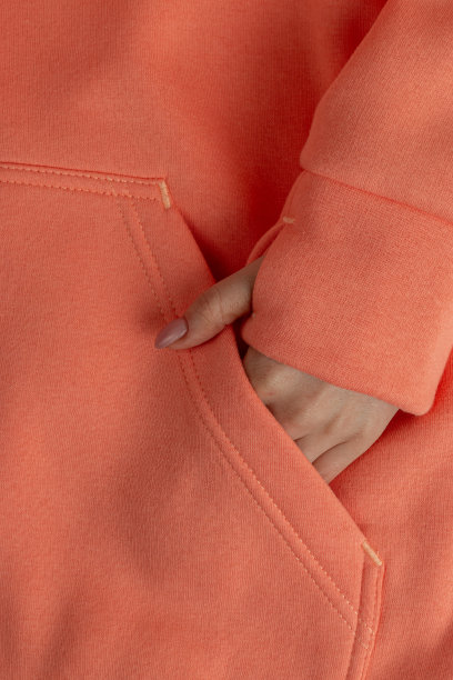 一个女孩的手在运动衫口袋里的特写镜头。一张照片的碎片，一个女人穿着运动衫在孤立的白色背景上。时尚运动装的广告。粉红色的图片下载