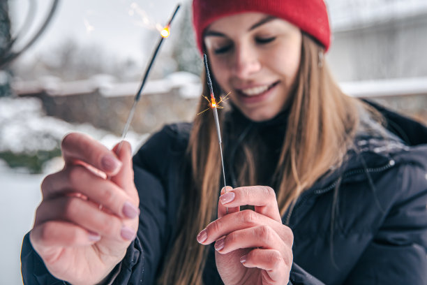 一名年轻女子的特写镜头，她手里拿着火花。图片下载