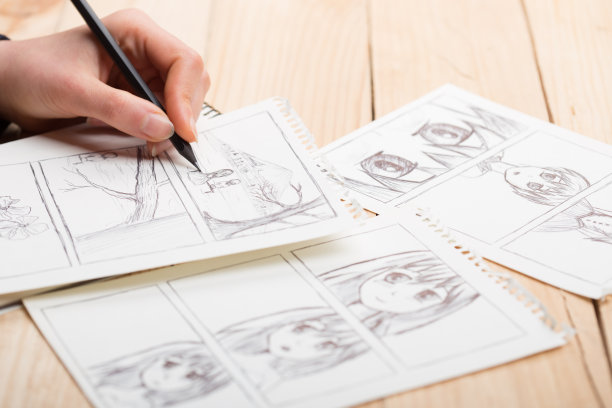 艺术家在工作室里画动画漫画书。木制办公桌，自然光。创意和灵感概念。图片下载