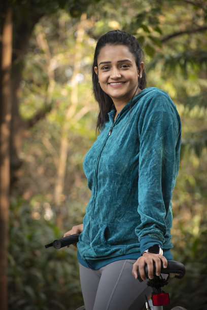 年轻女子骑自行车在公园股票照片图片下载