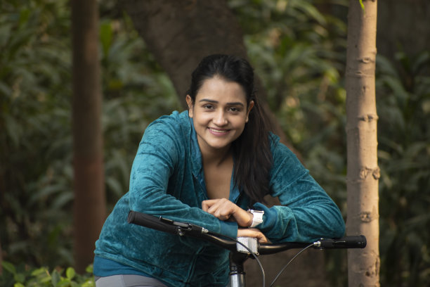 年轻女子骑自行车在公园股票照片图片下载