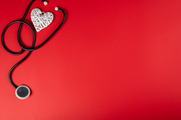 情人节和甜蜜的一天的概念。红色背景上的红心听诊器。爱情象征着健康和幸福。图片下载