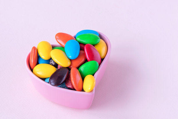 这是一种混合了多种颜色的巧克力馅的糖果，装在一个原始的粉色花瓶里，形状是心形的。图片下载