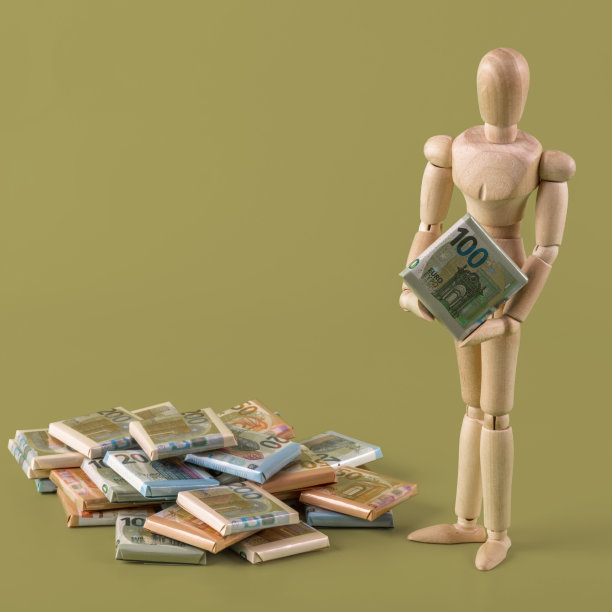 有象征意义的木制人和包裹在印有不同面值欧元钞票的纸中的糖果图片下载