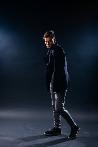 一张英俊的下颌轮廓分明的年轻人的肖像，戴着围巾，在一个黑色背景的工作室里摆姿势。图片下载