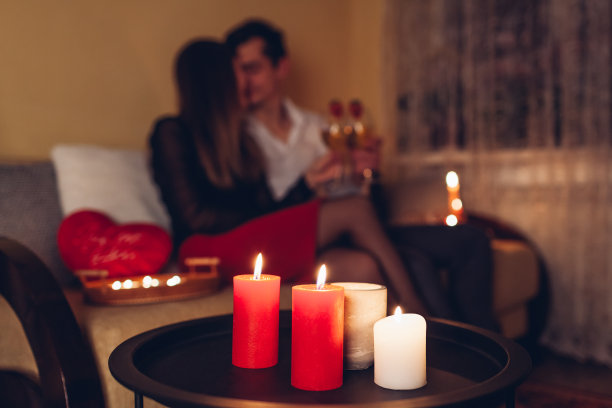 燃烧蜡烛的特写。情人节情侣在家里喝着酒庆祝爱情图片下载