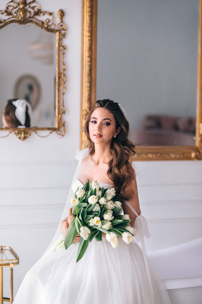 美丽的新娘穿着婚纱，捧着捧花坐在工作室里图片下载