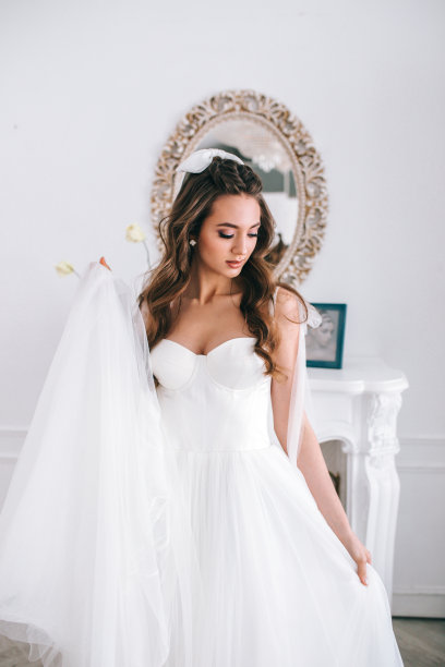 迷人的年轻新娘在结婚礼服站在工作室和向下看图片下载
