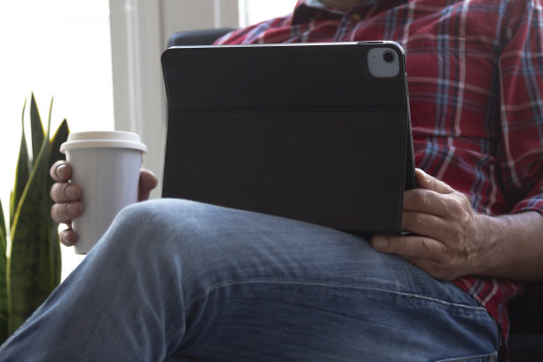 潮人坐在沙发上，拿着数码平板电脑和咖啡图片下载