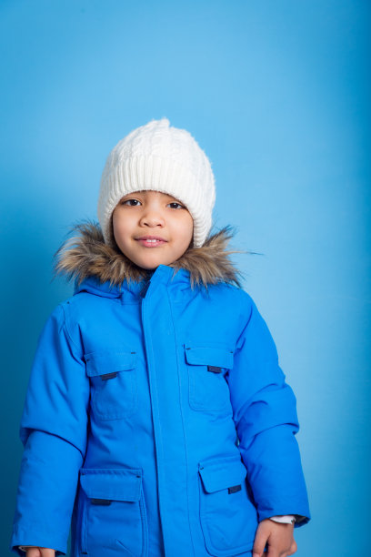 小亚洲女孩的肖像在蓝色的背景蓝色冬天的衣服图片下载