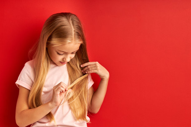 漂亮的小姑娘在检查她的发梢图片下载