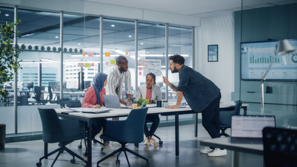 多民族办公室会议室:由四位创意企业家组成的多元文化团队，畅谈成长策略。多元化的年轻商人在数字电子商务初创公司工作。图片下载