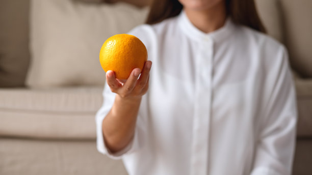一个年轻女子手里拿着一个橘子的特写图像图片下载