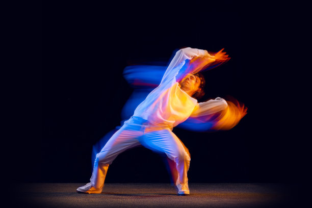 青年舞蹈。动态肖像的嘻哈舞者在行动，运动孤立在黑暗的背景在混合霓虹灯。青春文化、嘻哈、风格、时尚图片下载