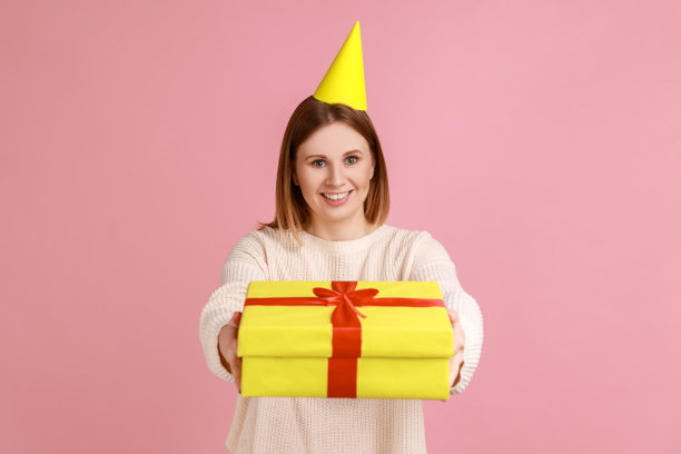 派对上的女人在送礼物盒，看着镜头，祝贺朋友生日。图片下载