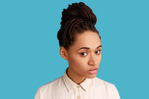 可爱的女人，留着脏辫，有着完美的皮肤，带着严肃的表情看着镜头。图片下载