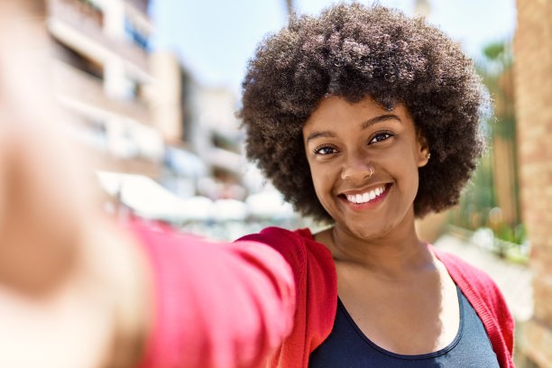年轻的非洲裔美国女孩微笑着在城市的智能手机旁自拍。图片下载