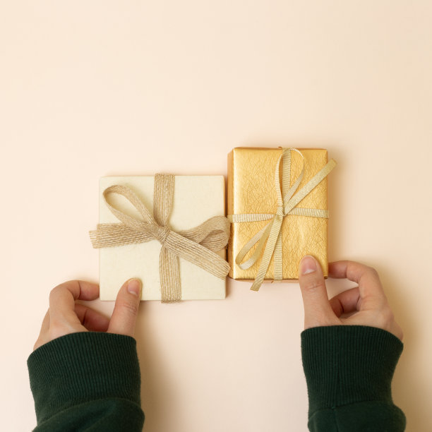 女性手拿粉色背景的礼品盒。俯视图，复制空间图片下载