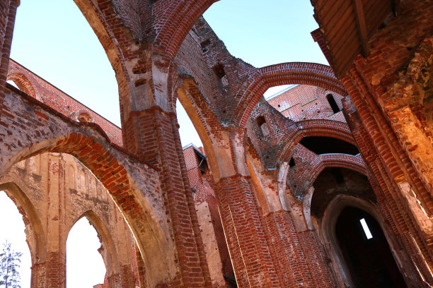 一座废弃的古老寺庙的砖拱——风化的大教堂的美丽建筑景观，背景是蓝色的天空图片下载