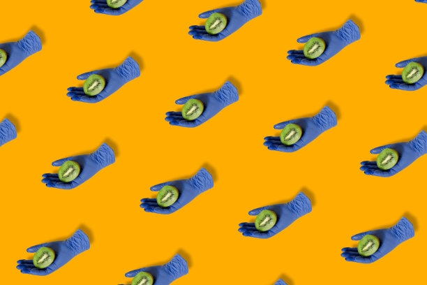 艺术图案与蓝色医用手套持有新鲜猕猴桃在充满活力的橙色背景。平面构成。健康的生活方式理念。图片下载