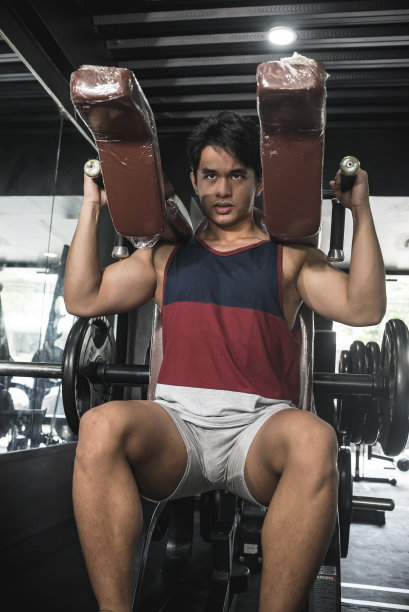 一个专注的亚洲男性在健身房做下蹲。锻炼臀大肌和四头肌。垂直拍摄。图片下载