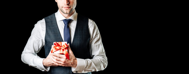 礼物的人。快乐的年轻商人拿着惊喜的礼盒礼物，黑色背景上孤立的红丝带。黑色星期五，情人节祝贺横幅。图片下载