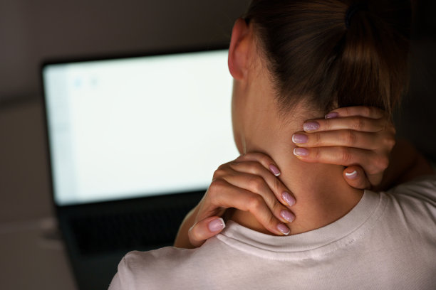 年轻女性在电脑上工作后脖子痛。按摩颈部以减轻疼痛图片下载