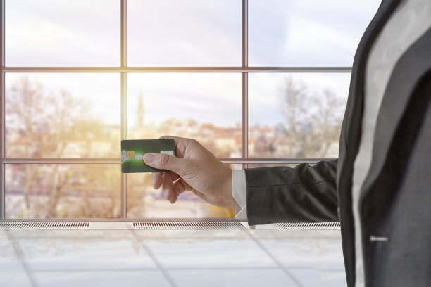 男士在办公室里穿着优雅的定制西装，手里拿着银行信用卡图片下载