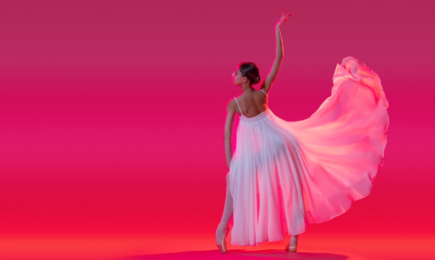 优雅的芭蕾舞演员在足尖鞋跳舞，在粉红色的背景白色长裙图片下载