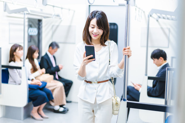 一位年轻女子在火车上使用智能手机图片下载