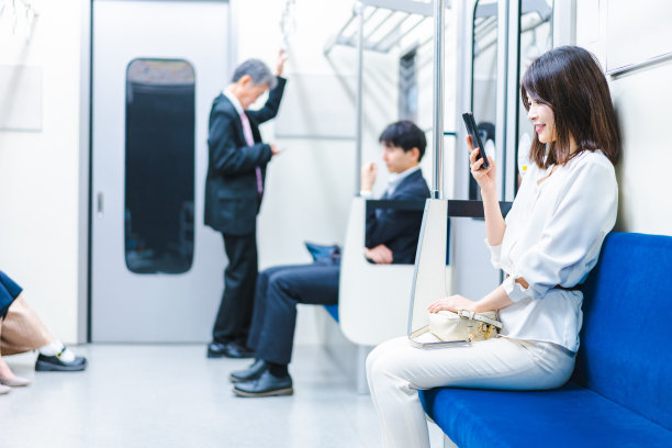 一位年轻女子在火车上使用智能手机图片下载