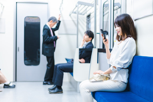 一位年轻女子在火车上使用智能手机图片下载