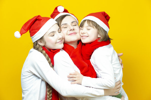 三个美丽的白人女士的肖像不同的年龄在圣诞帽和休闲衣服一起玩在时髦的黄色背景。图片下载