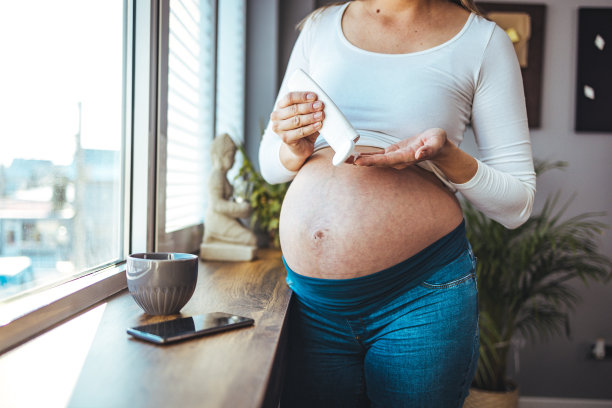 在腹部涂抹保湿霜。图片下载