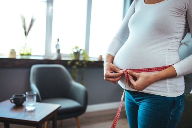 孕妇用厘米卷尺测量肚子，以记录胎儿的发育情况。图片下载