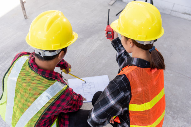 建筑师与客户讨论并协助在施工现场绘制建筑平面图图片下载
