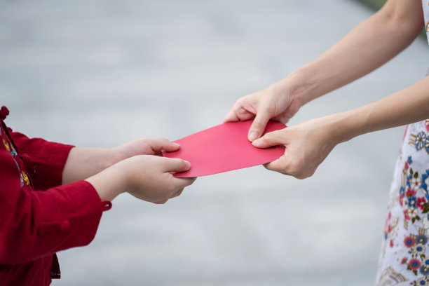亚洲妇女递红包给男孩的手。近距离和选择性聚焦。中国的新年节日。给对方钱。家庭与父母观念图片下载