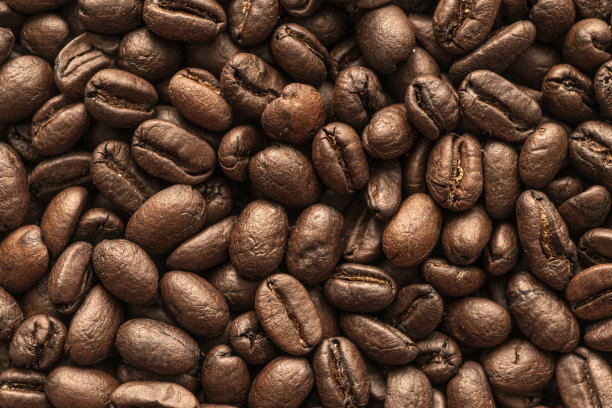 咖啡豆的背景。关闭了。桌子上磨砂咖啡豆的微距照片。图片下载
