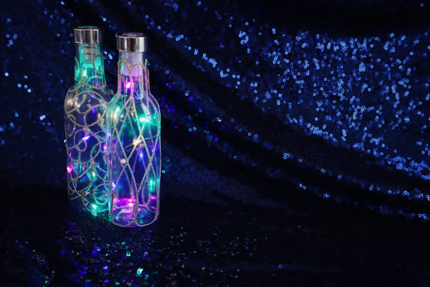 仙女灯在瓶子上美丽的深蓝色亮片织物背景图片下载